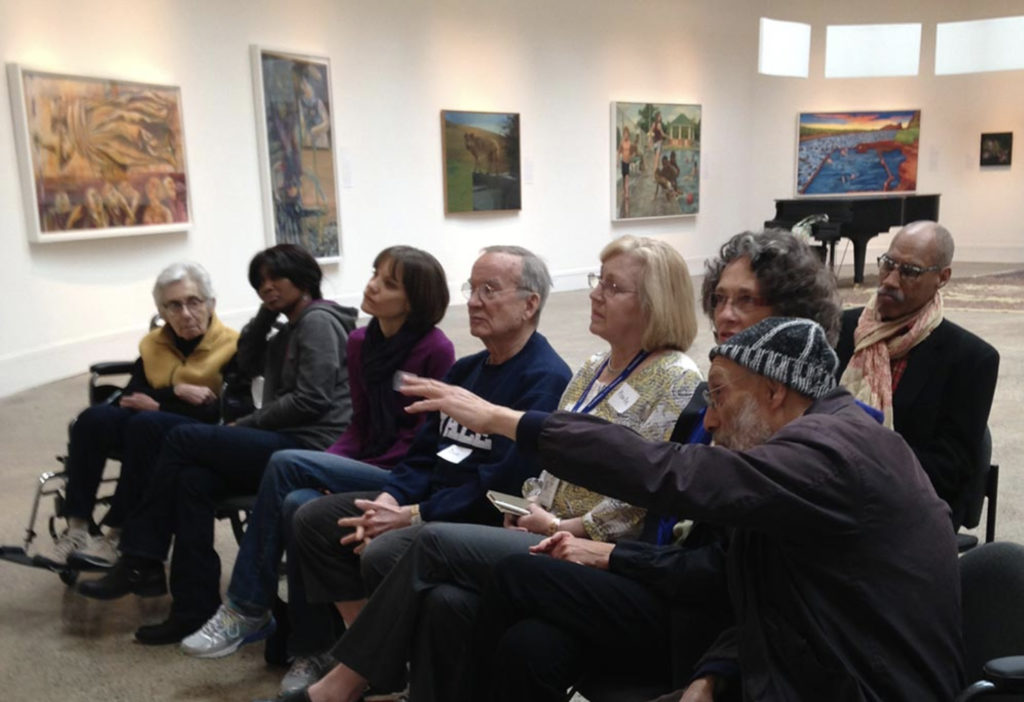 Carl points excitedly at an artwork as other participants listen intently to his comments