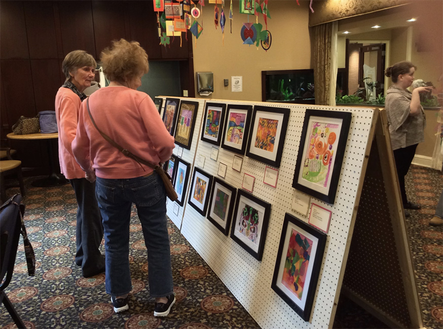 Two ARTZ participants view works made by people living with dementia at an exhibition