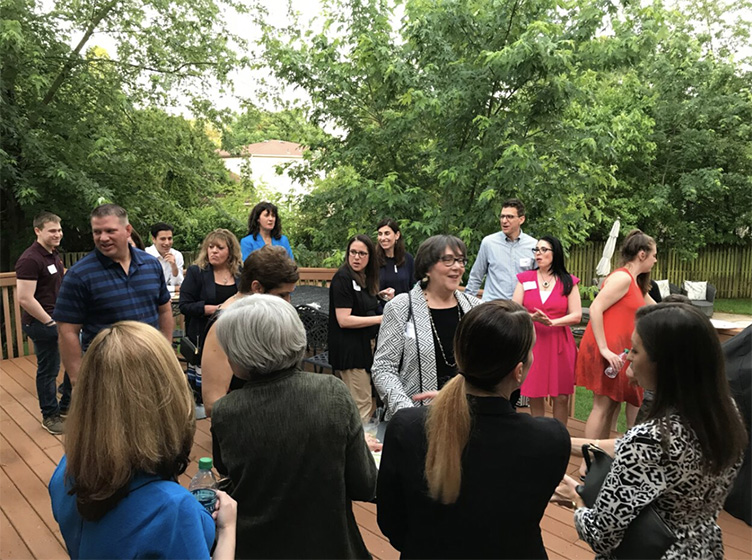 A group people gathers on a deck at the Meet and Greet