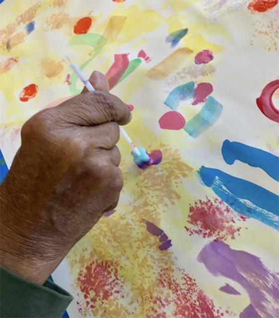 The hand of an ARTZ participant paints a colorful picture