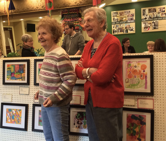 Two ARTZ participants stand at an exhibition of works made by people living with dementia
