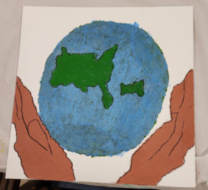 A painting of two hands gently clasped around the earth
