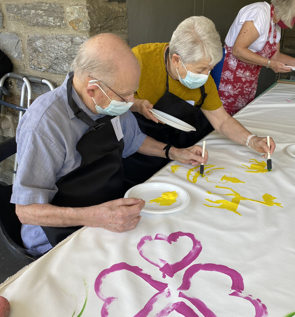 Don and Jackie Kahn painting a banner out front of Woodmere Art Museum using yellow paint